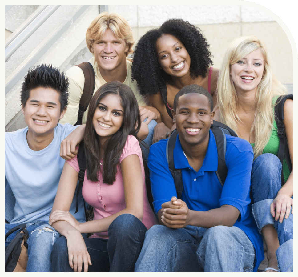 GettyImages-164072436 (1) A group of people sitting on steps smiling for the camera.